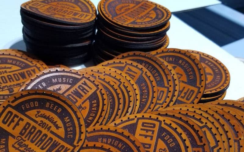 A CO2 laser machine precisely engraving a detailed company logo onto a leather pieces