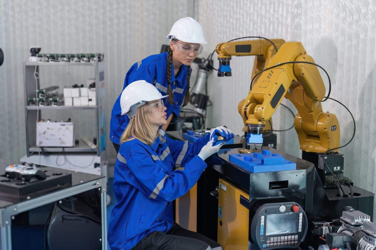 female senior robotic engineer in modern factory teach new comer operate and maintenance robot arm.jpg