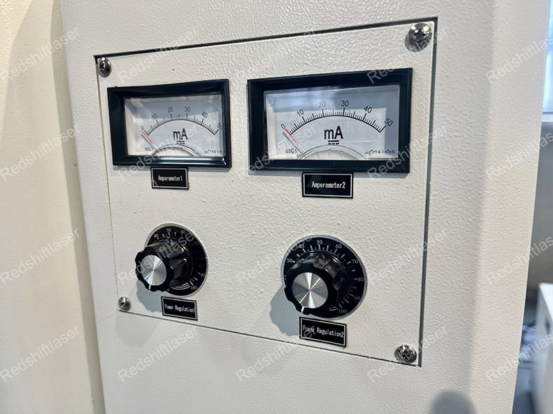 A CO2 laser machine in a workshop with a warning sign visible