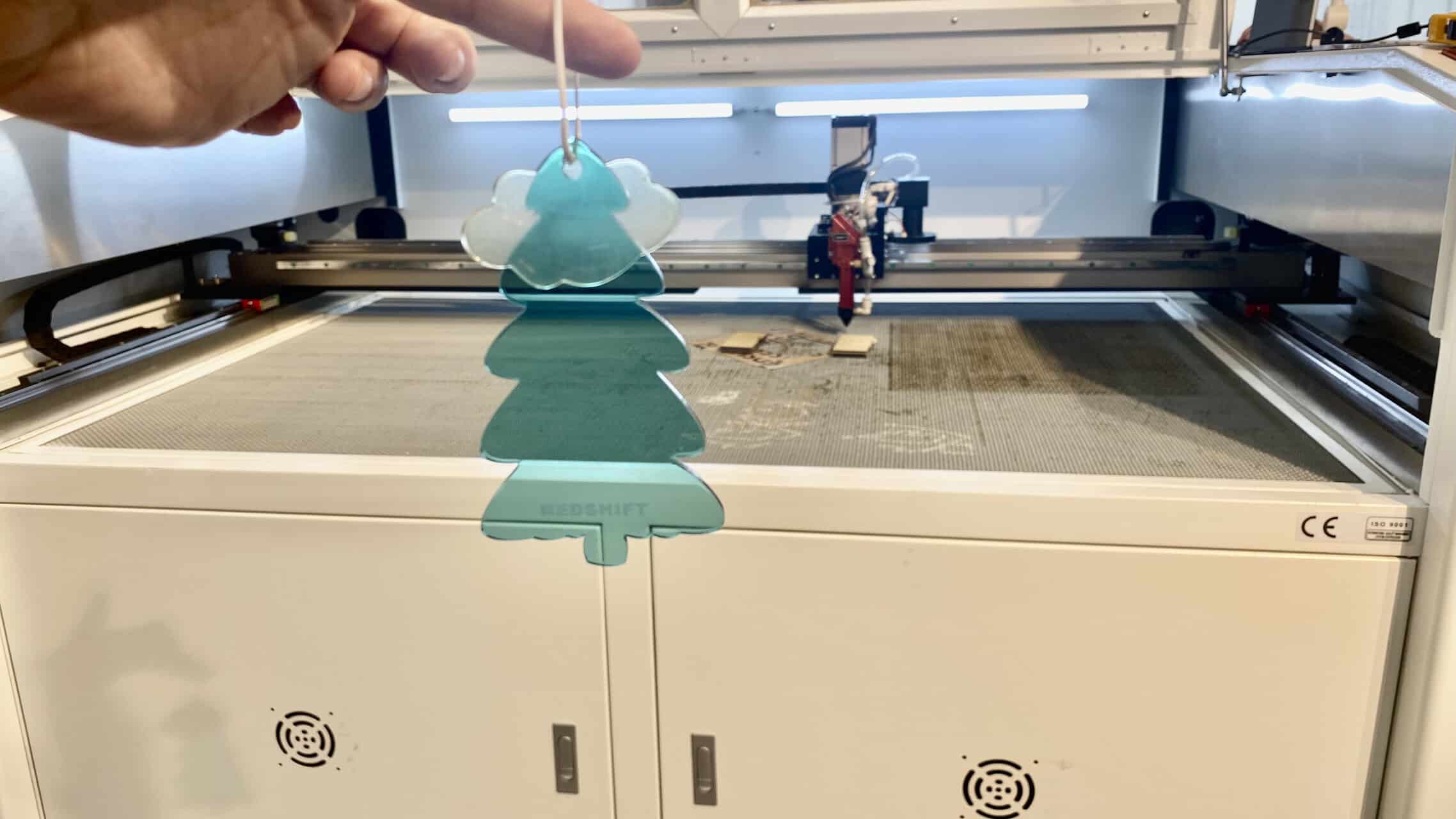 A split image showing a simple name engraved on a leather keychain and a complex mandala pattern on a large wooden box