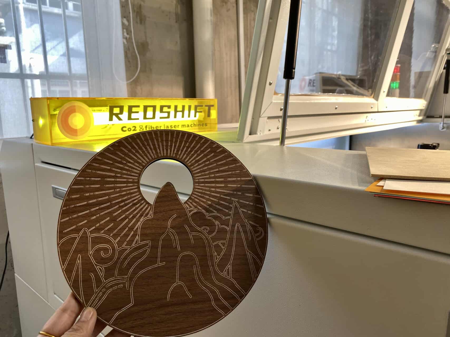 A collage of laser engraved wood products: a company logo on a cutting board, a detailed photo on a plaque, and intricate patterns on a phone case