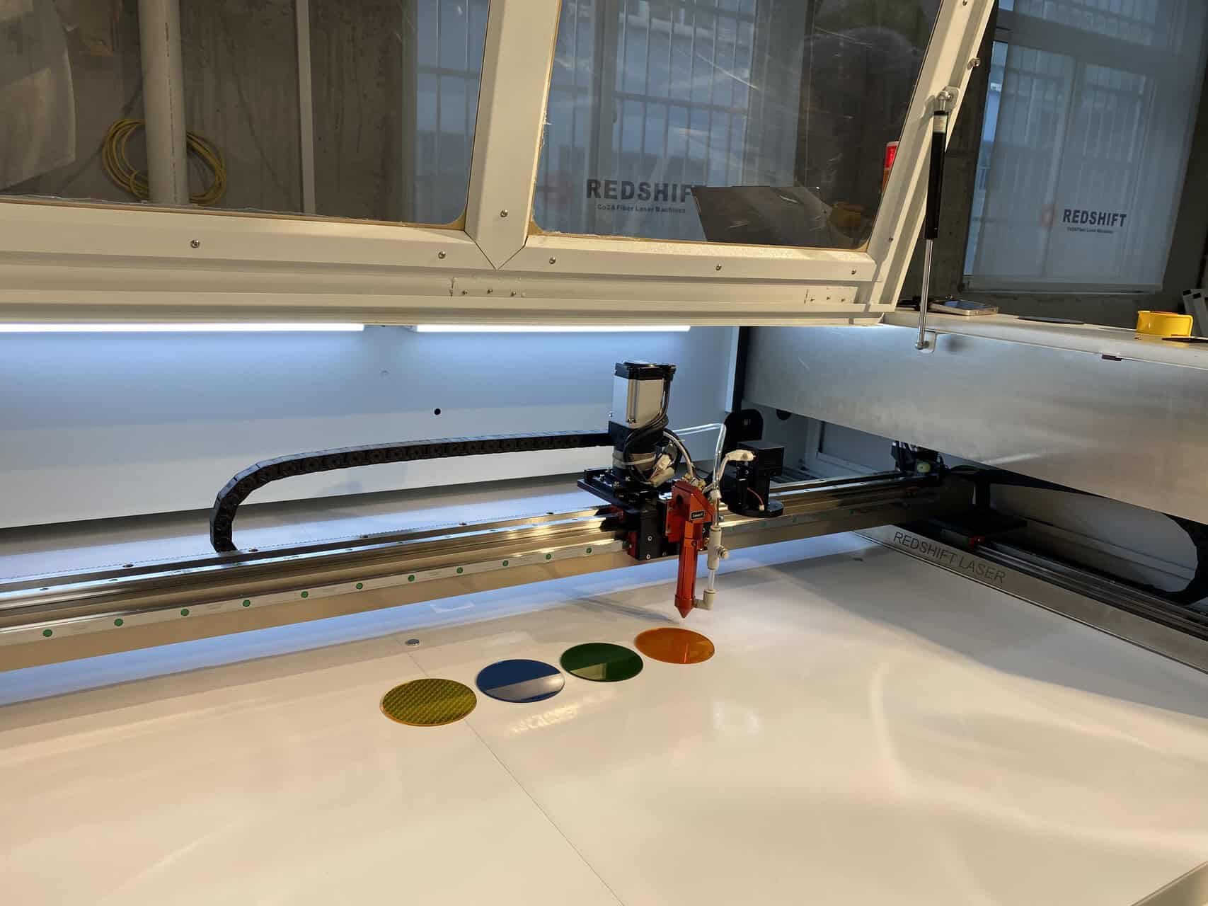 How a CO2 Laser Cutter Works Diagram showing a CO2 laser beam being focused by a lens onto a sheet of plastic