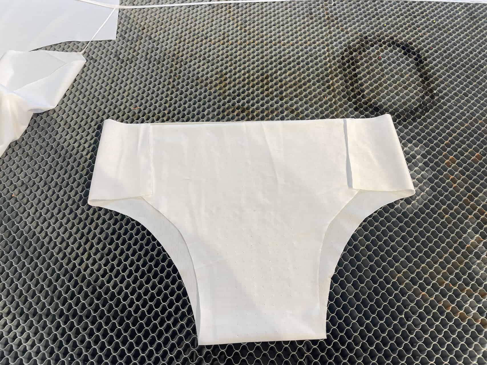 A large a stack of precisely cut garment patterns on an industrial laser cutting bed