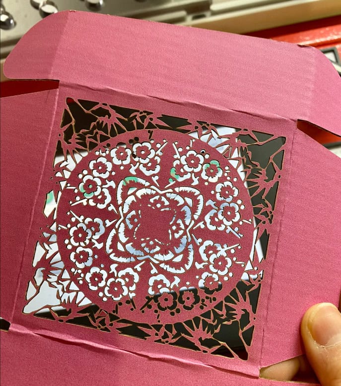 A close-up of a laser nozzle with a strong air-assist jet blowing vaporized material away from the cut kerf