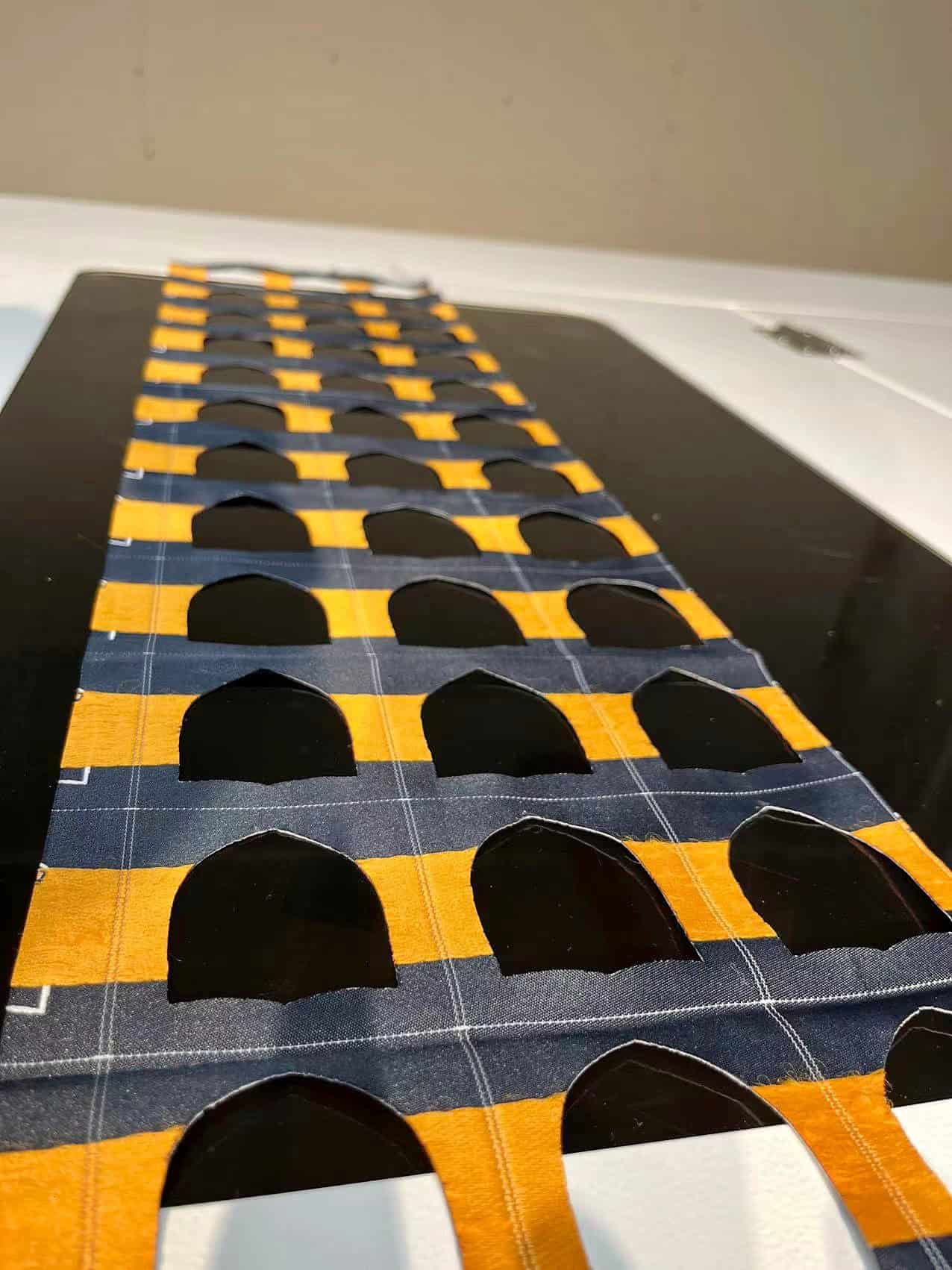 An extreme close-up showing a laser-cut patch being peeled off a backing sheet, revealing the perfect kiss-cut outline