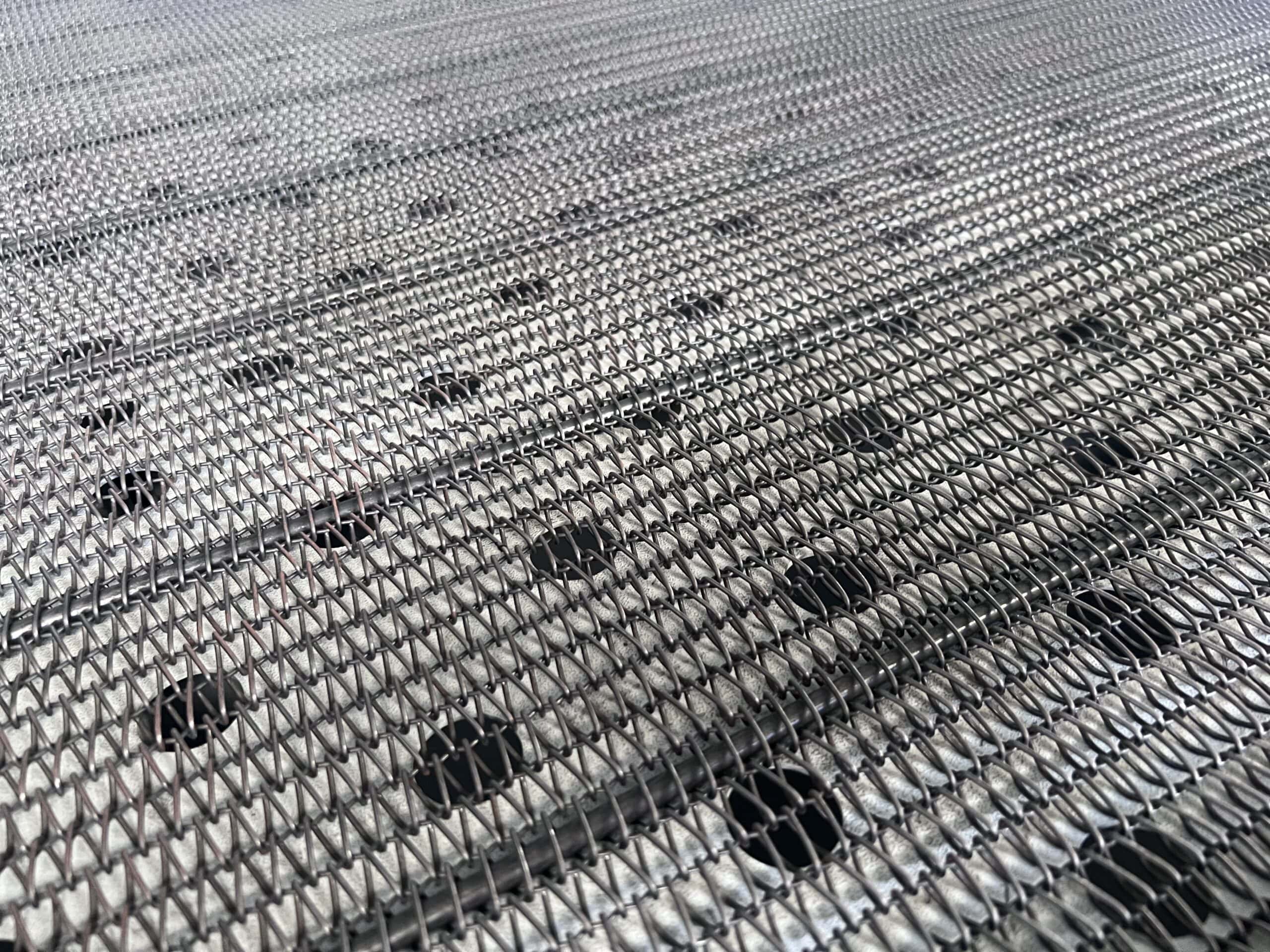 Wire mesh conveyor bed with low-perforation metal backing plate